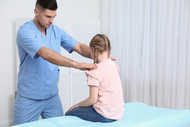 Photo of Orthopedist examining child in clinic. Scoliosis treatment