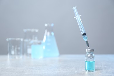 Photo of Syringe and vial on light grey table. Space for text