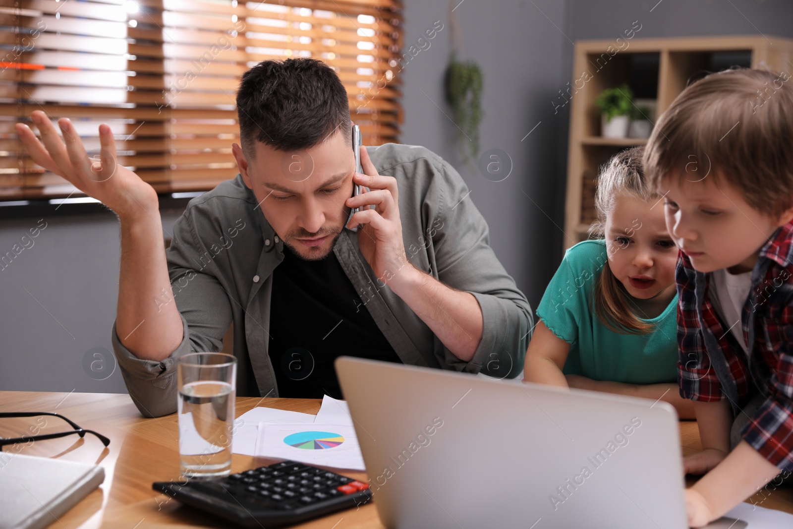 Photo of Overwhelmed man combining parenting and work at home