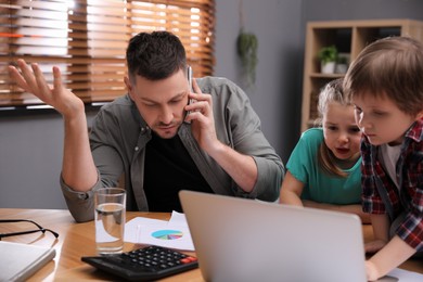 Photo of Overwhelmed man combining parenting and work at home