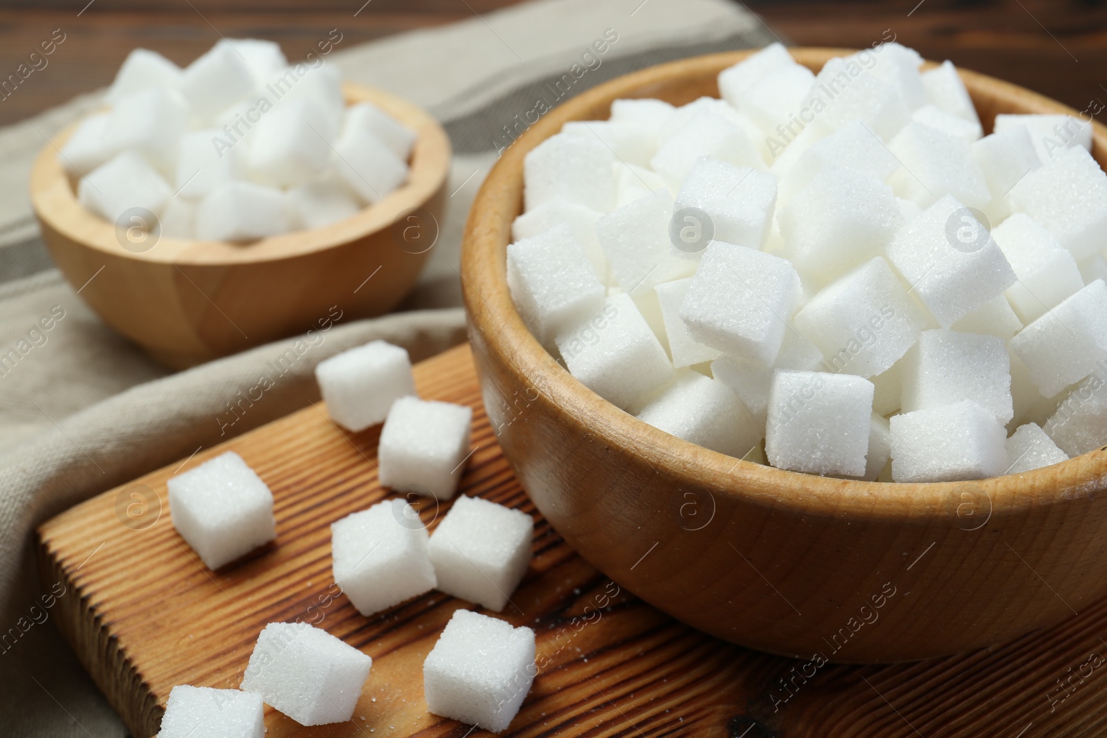 Photo of White sugar cubes on wooden table, closeup