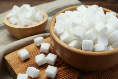 Photo of White sugar cubes on wooden table, closeup