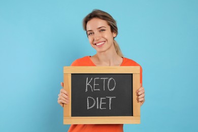 Photo of Woman holding blackboard with phrase Keto Diet on light blue background