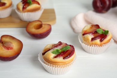 Photo of Delicious cupcakes with plums on white wooden table