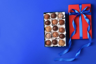 Box with delicious chocolate candies on blue background, flat lay. Space for text