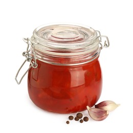 Photo of Glass jar of delicious canned lecho, garlic and peppercorns on white background