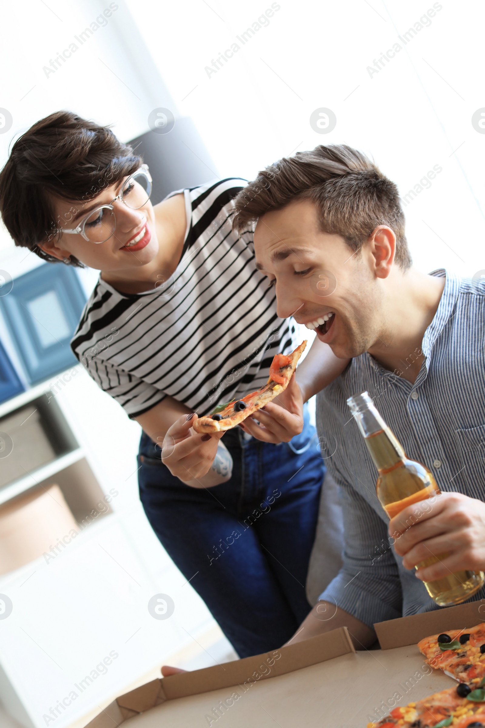 Photo of Young couple eating delicious pizza indoors
