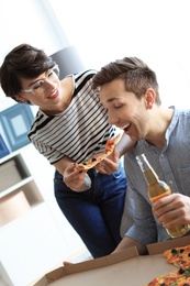 Young couple eating delicious pizza indoors