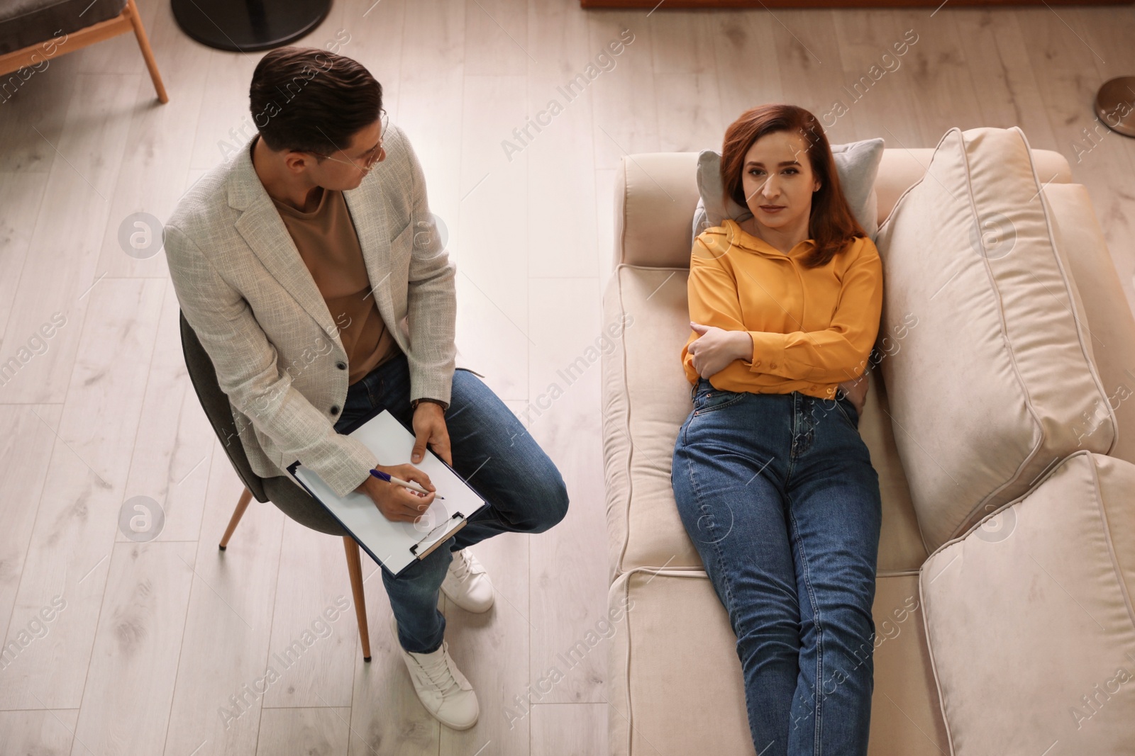 Photo of Professional psychotherapist working with patient in office, above view