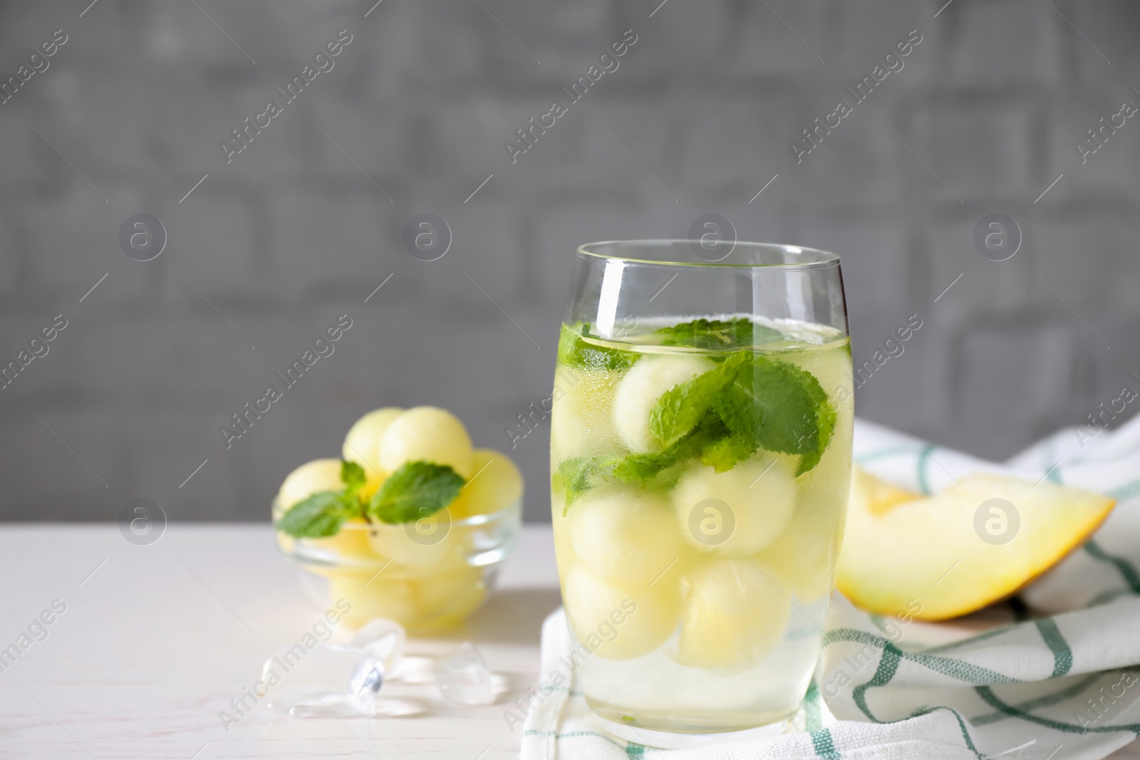 Photo of Tasty melon ball drink on white table. Space for text