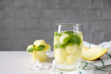 Photo of Tasty melon ball drink on white table. Space for text