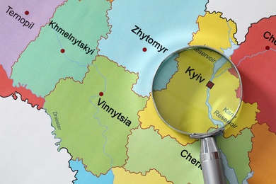 Photo of Metal magnifying glass above Kyiv region on map of Ukraine, closeup