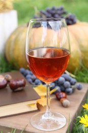 Photo of Glass of wine on wooden board outdoors. Autumn picnic