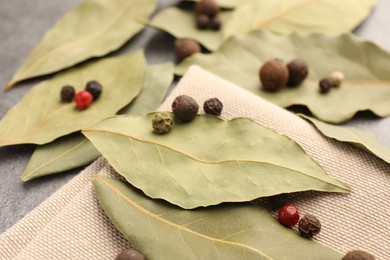 Photo of Aromatic bay leaves and spices on light gray table, closeup