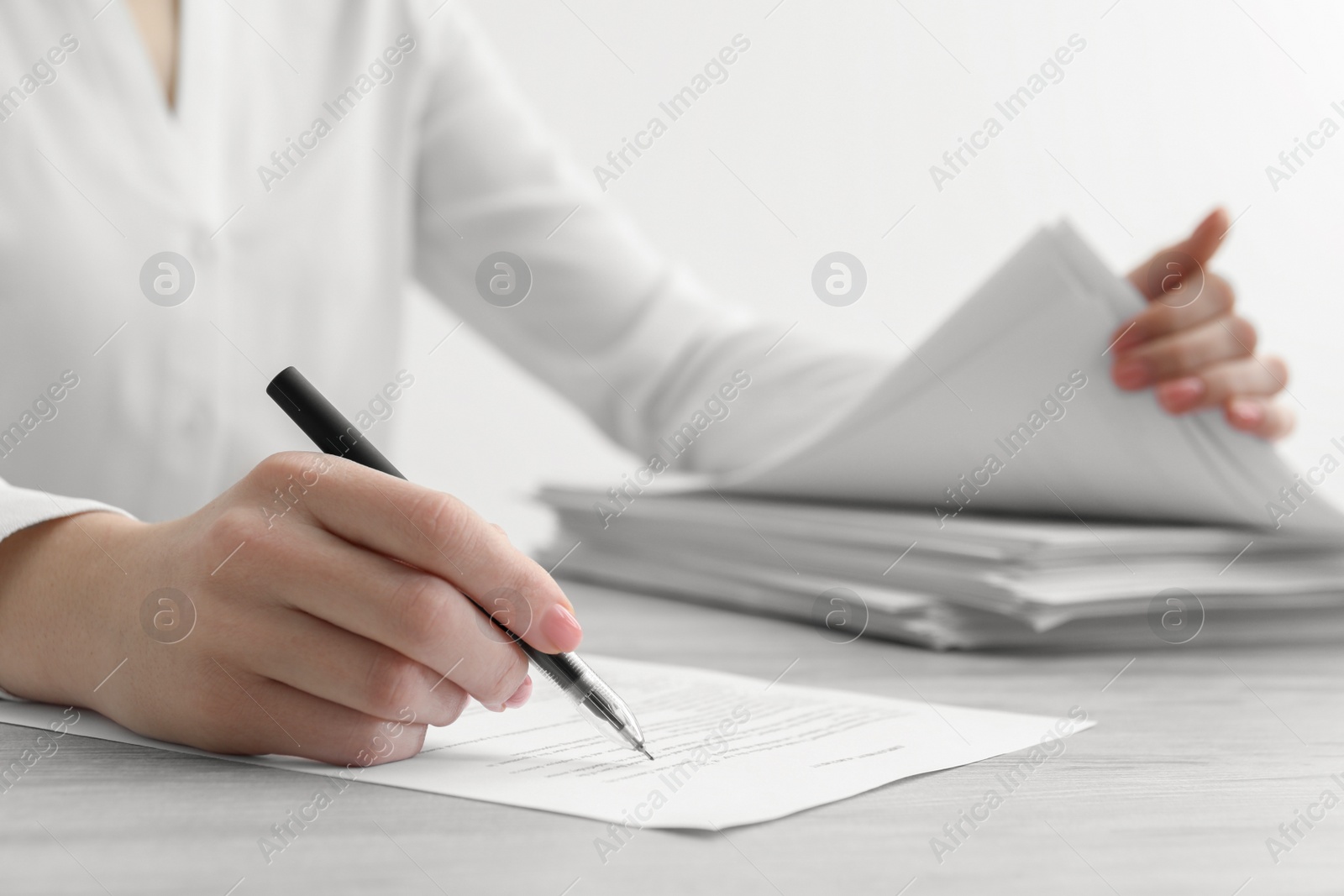 Photo of Woman signing documents at wooden table in office, closeup. Space for text