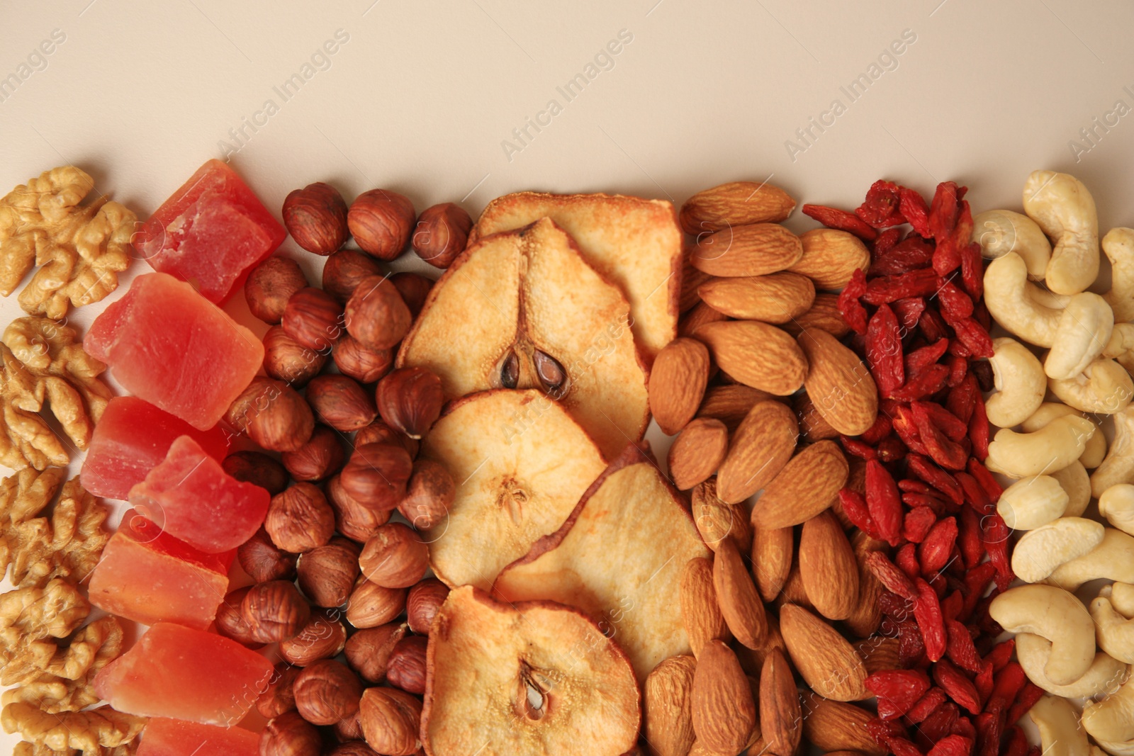 Photo of Mix of delicious dried nuts and fruits on beige background, flat lay