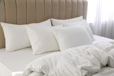 Photo of Many soft pillows and blanket on large comfortable bed indoors