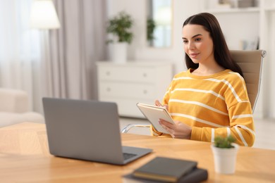 Young woman watching webinar at table in room