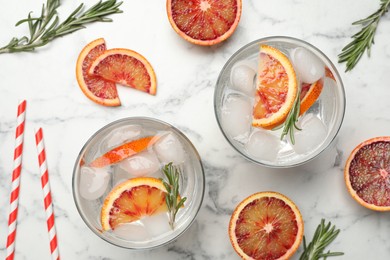 Photo of Delicious refreshing drink with sicilian orange and rosemary on white marble table, flat lay