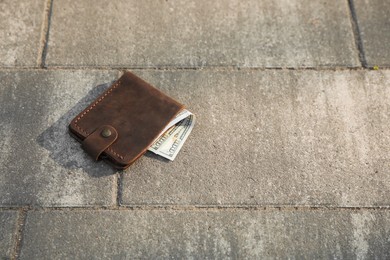 Brown leather purse on pavement outdoors, space for text. Lost and found