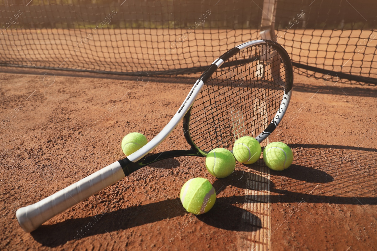 Photo of Tennis balls and racket on clay court