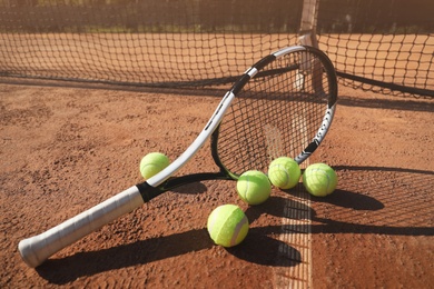 Tennis balls and racket on clay court