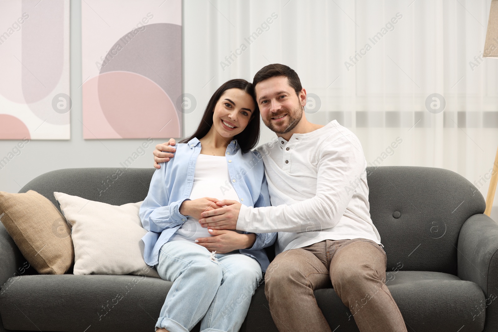 Photo of Portrait of happy pregnant woman with her husband on sofa at home