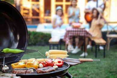 Photo of Barbecue grill with tasty fresh food and blurred people on background