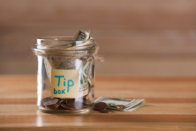 Glass jar with tips on wooden table, closeup. Space for text