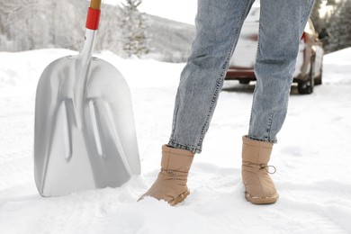 Woman with shovel outdoors on snowy winter day, closeup
