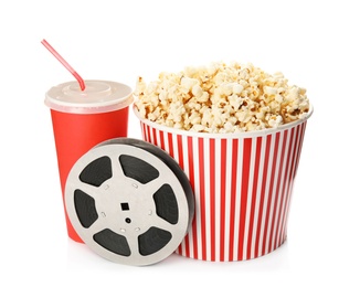 Photo of Bucket with tasty popcorn, beverage and film reel on white background