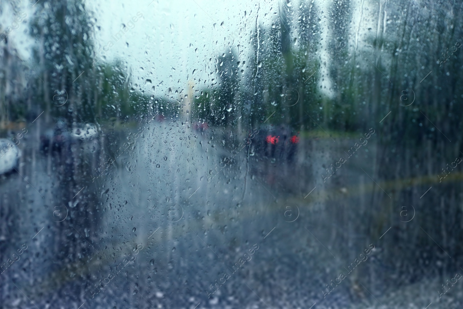 Photo of Blurred view of city street through wet window on rainy day