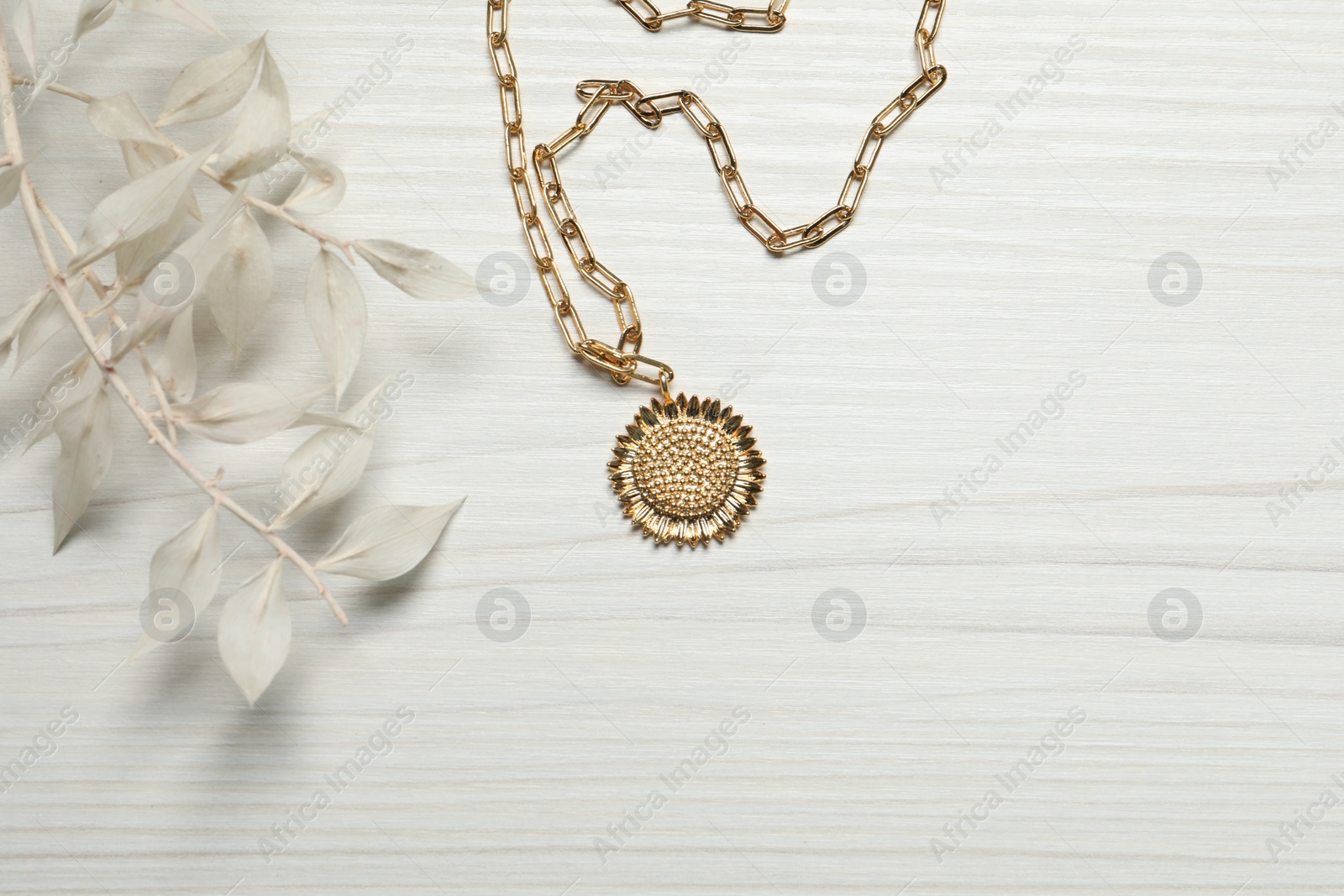 Photo of Elegant necklace and dry leaves on white wooden table, top view. Space for text