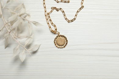 Elegant necklace and dry leaves on white wooden table, top view. Space for text