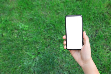 Photo of Woman using smartphone on green grass outdoors, above view. Space for text