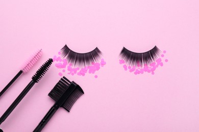 Photo of Flat lay composition with false eyelashes, confetti, makeup and mascara brushes on pink background