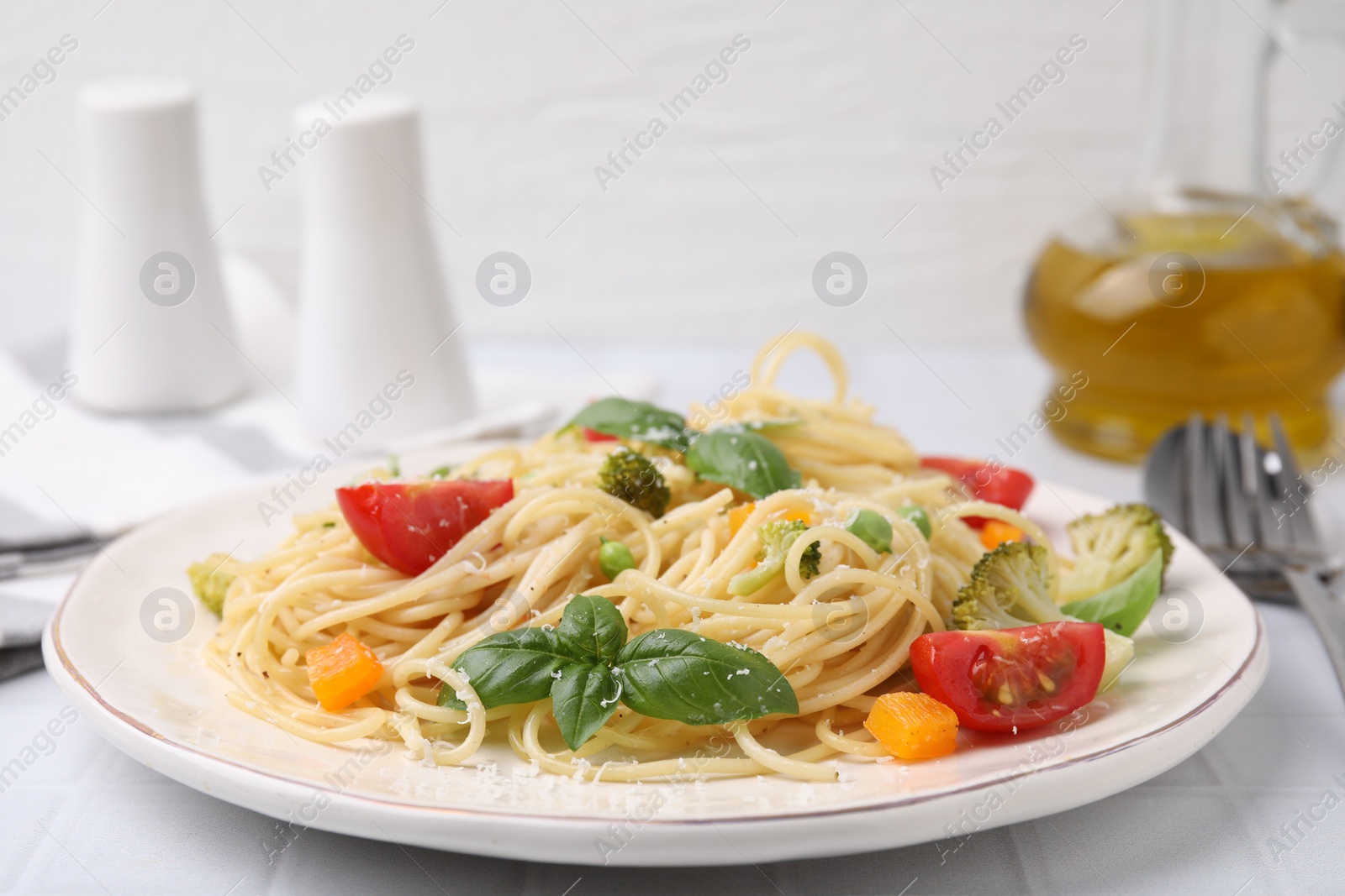 Photo of Delicious pasta primavera with tomatoes, basil and broccoli on white table, closeup