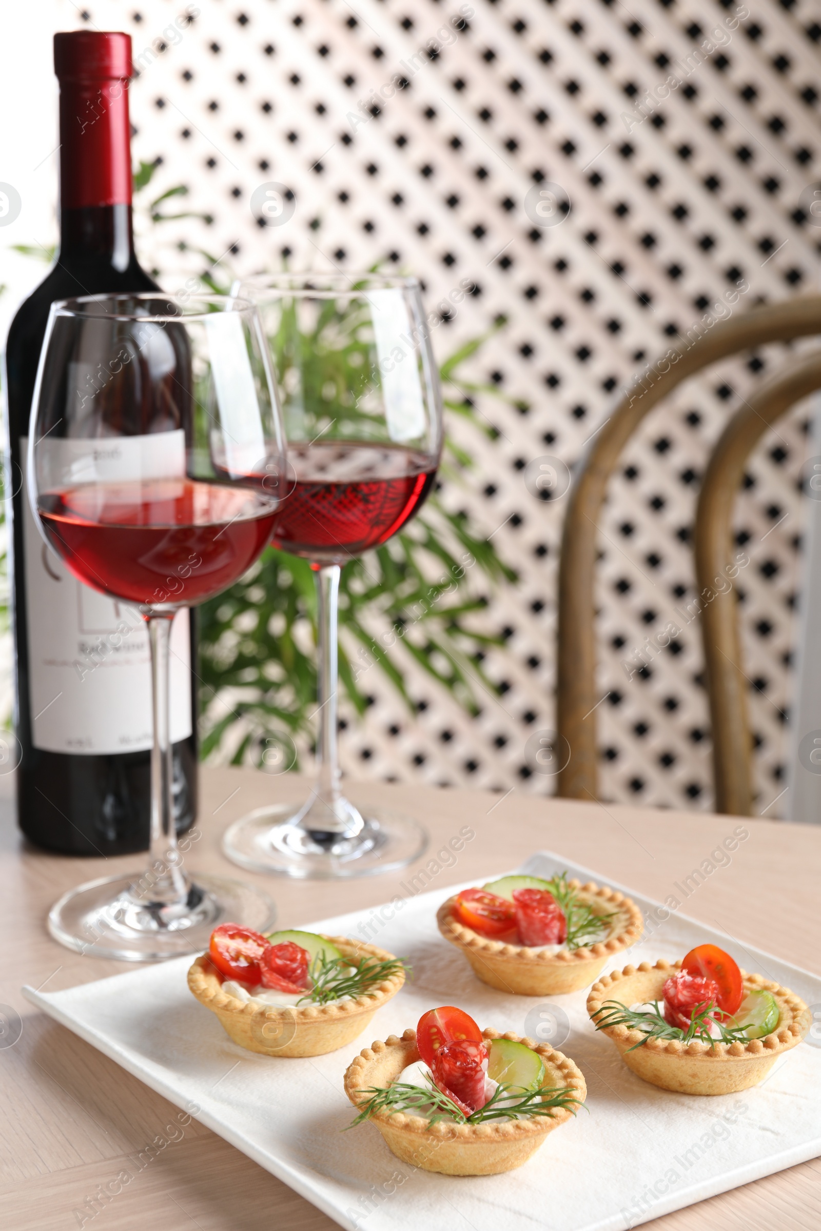 Photo of Delicious canapes with dry smoked sausages, cream cheese and vegetables served on wooden table