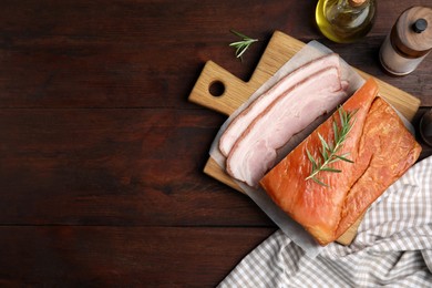 Photo of Delicious smoked bacon with rosemary on wooden table, flat lay. Space for text