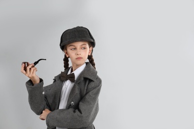 Photo of Cute little detective with smoking pipe on grey background. Space for text