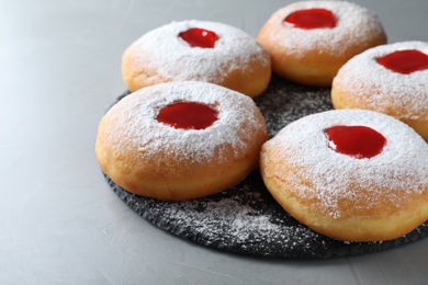 Photo of Hanukkah doughnuts with jelly and sugar powder served on grey table, closeup