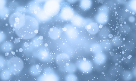 Abstract snowfall on light blue background, bokeh effect