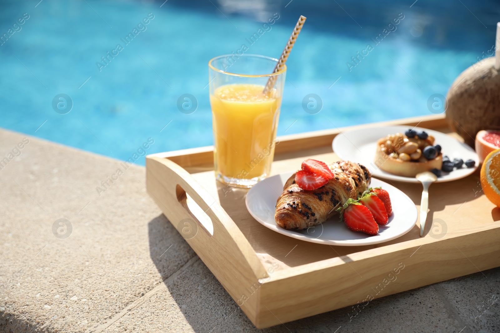 Photo of Tray with delicious breakfast near swimming pool, closeup