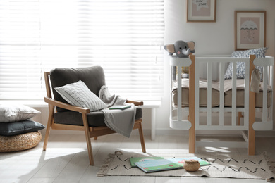 Photo of Baby room interior with crib and armchair. Idea for design