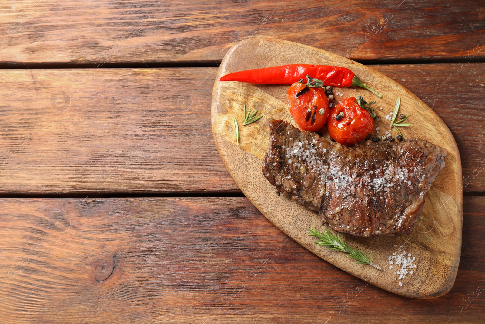 Photo of Delicious roasted beef meat, vegetables and spices on wooden table, top view. Space for text