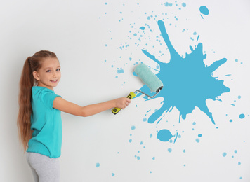 Little girl painting white wall with roller brush 