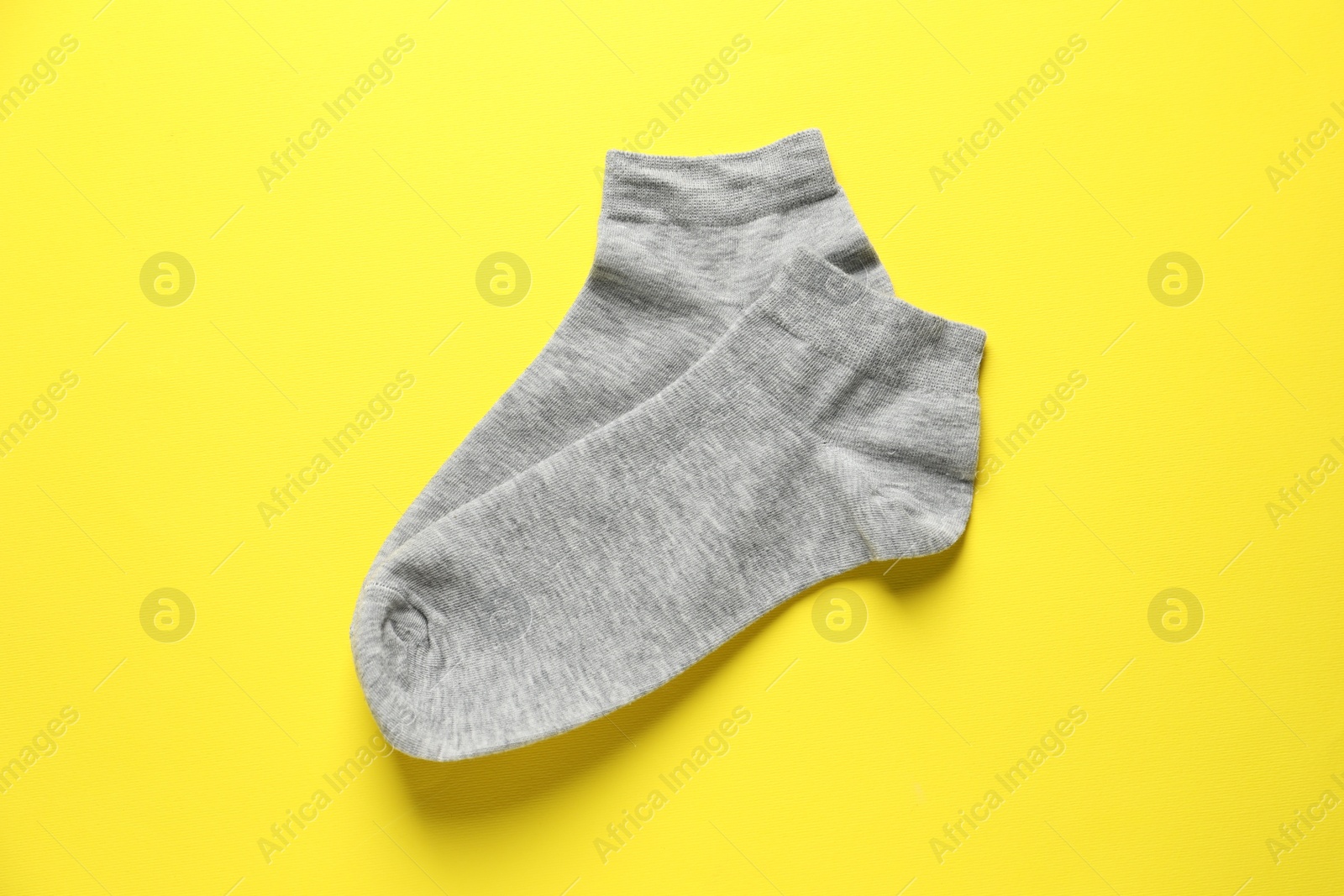 Photo of Pair of grey socks on yellow background, flat lay