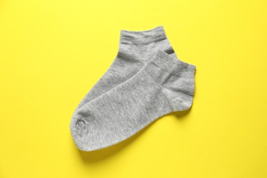 Pair of grey socks on yellow background, flat lay