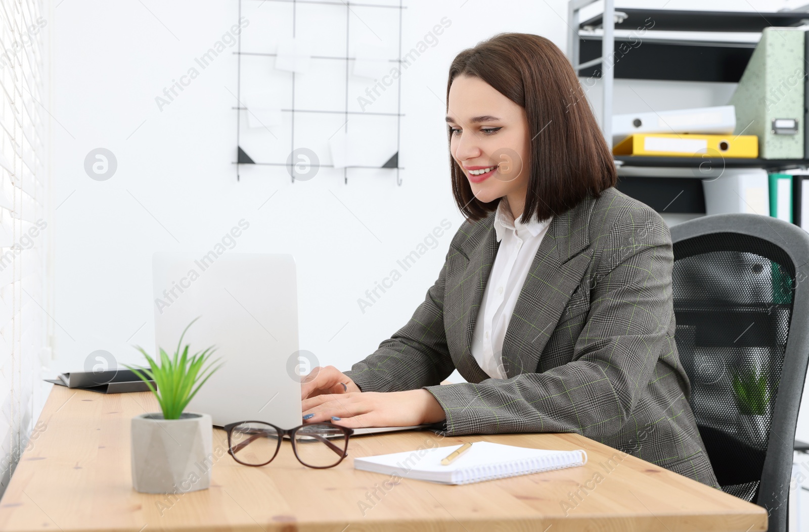 Photo of Happy young intern working at table in modern office