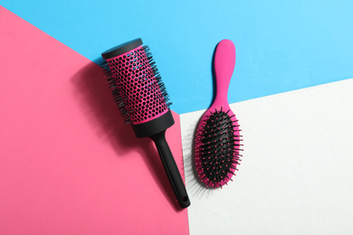New hair brushes on color background, flat lay
